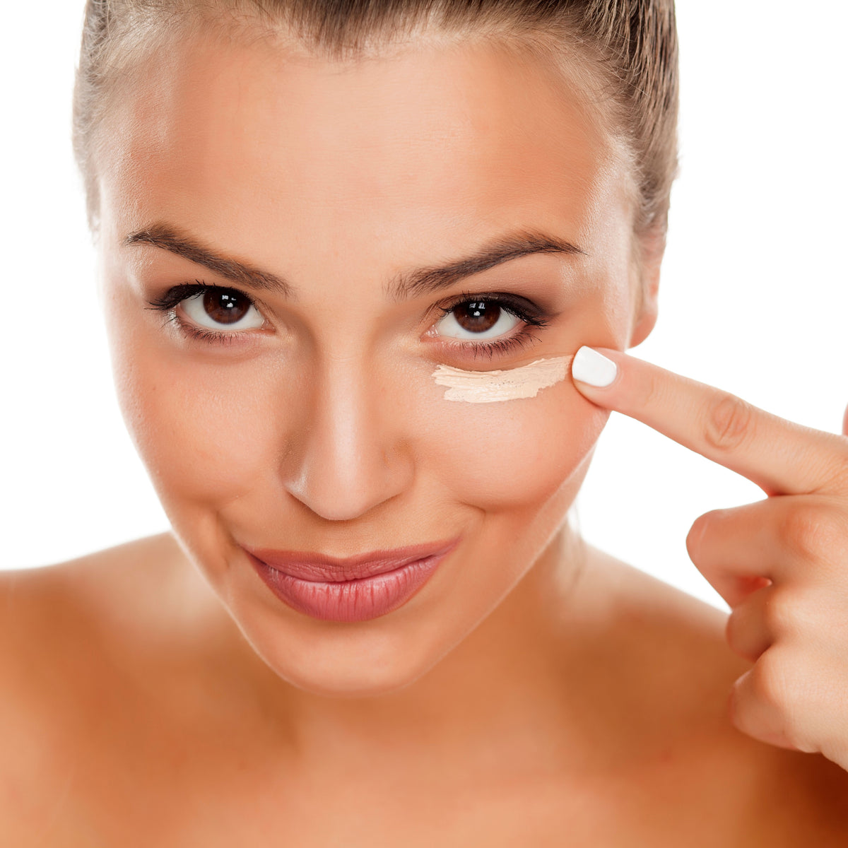 Woman applying concealer under her eye with a fingertip