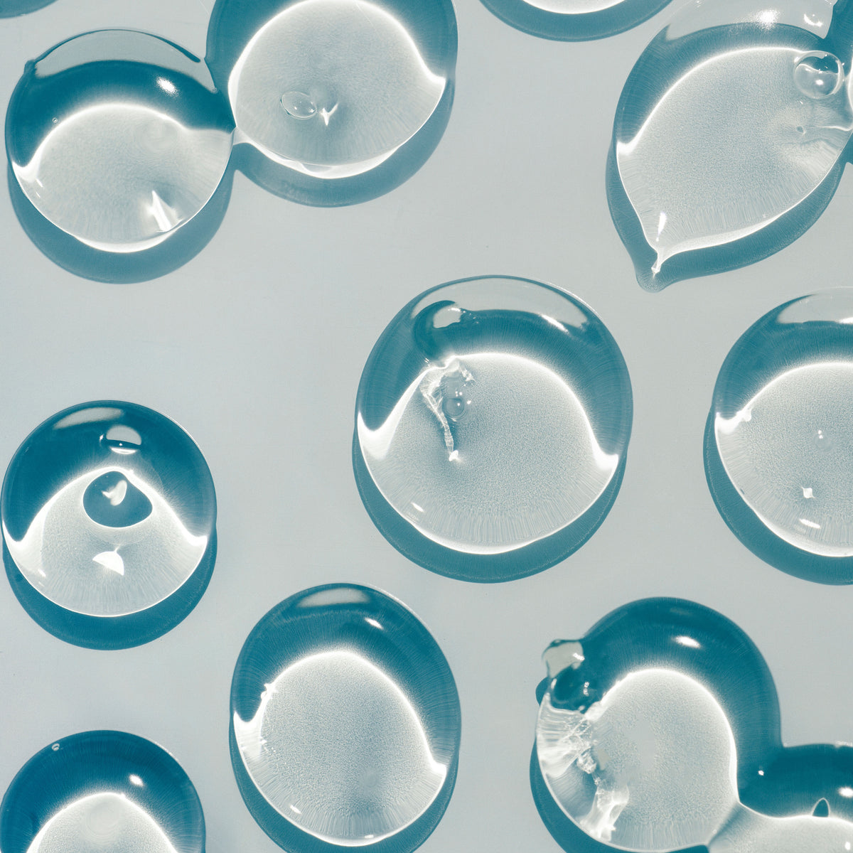 Clear serum droplets on a pale surface, macro