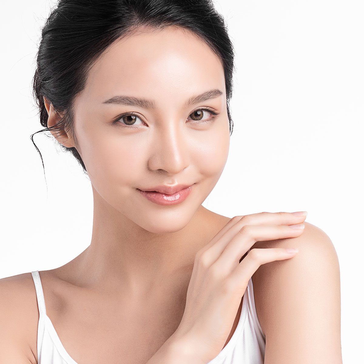 Woman with clear, luminous skin resting her hand near her shoulder