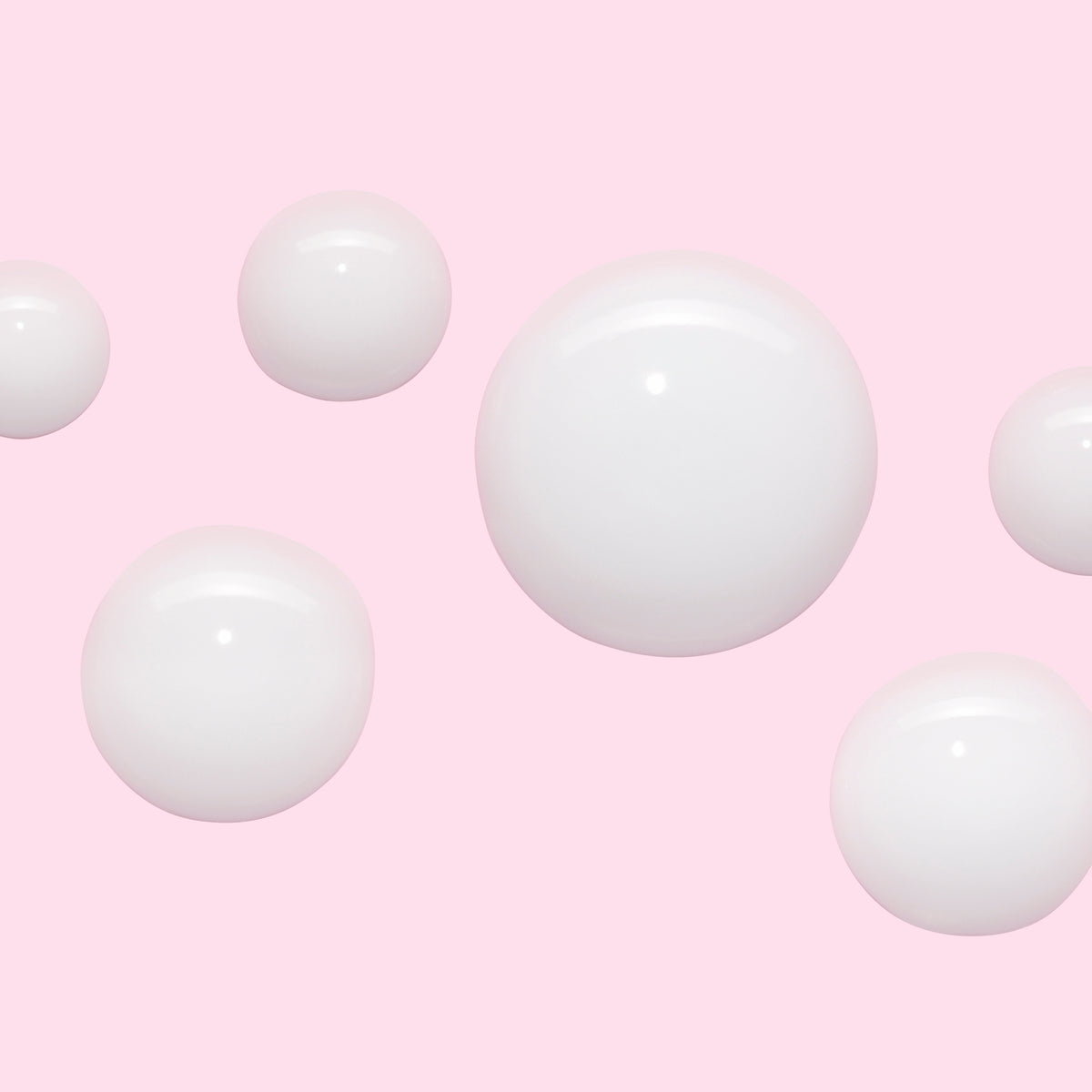 White cream spheres on a soft pink background