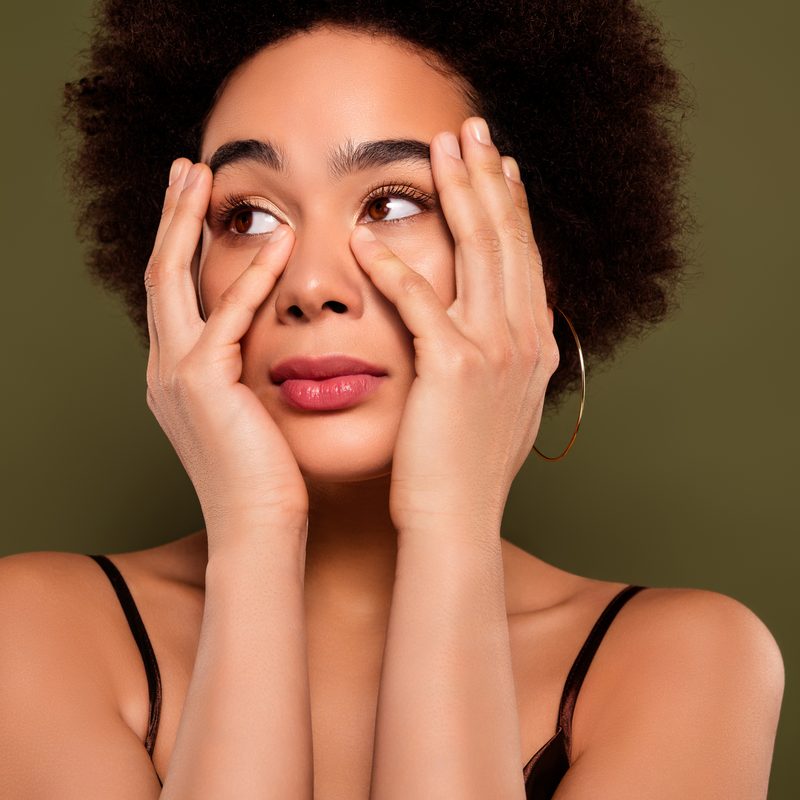 Woman with glowing skin resting her hands gently around her eyes